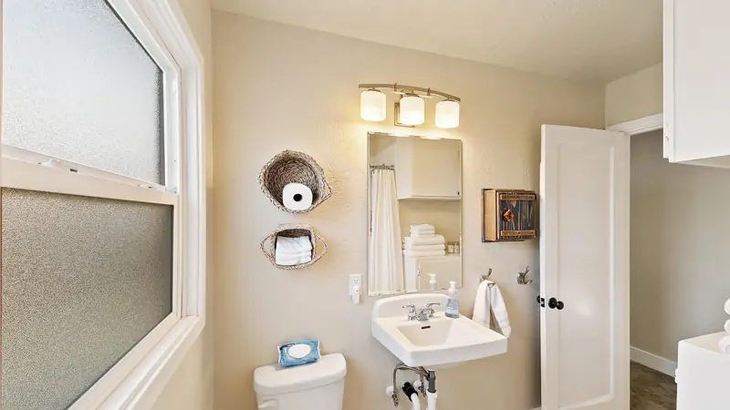 Bathroom with a pedestal sink, a lighted mirror, a frosted window and a toilet.