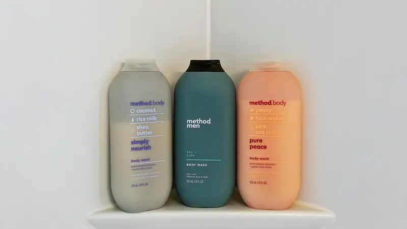 Three bottles of body wash on a shower shelf.