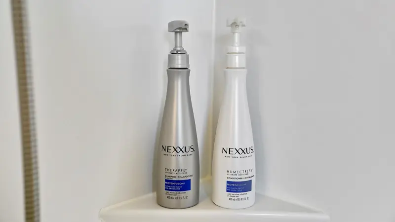 Bottles of shampoo and conditioner on a shower shelf.