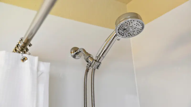 Handheld showerhead on a chrome hose above the tub.