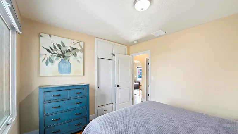 Second bedroom with a teal dresser, a botanical print and a built-in closet.