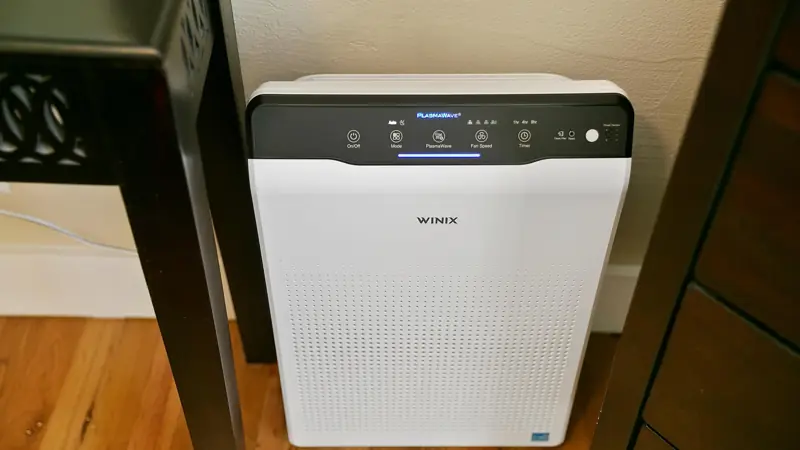 Winix air purifier on the floor beside the furniture.