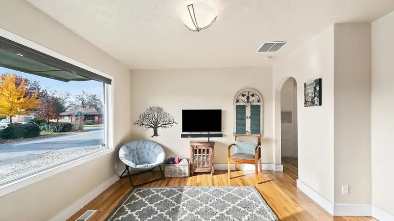 Living room with a large picture window, a round chair, a TV and an arched doorway to the hall.