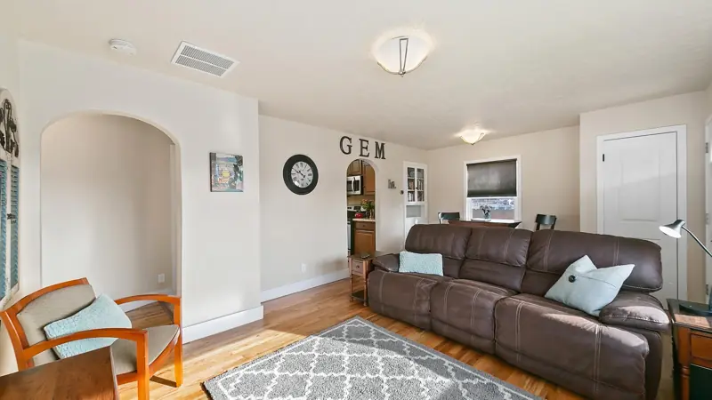 Living room with a reclining couch, an armchair, a patterned rug and an arched doorway.