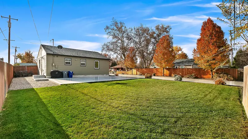 Backyard lawn with the home and parking pad behind it.