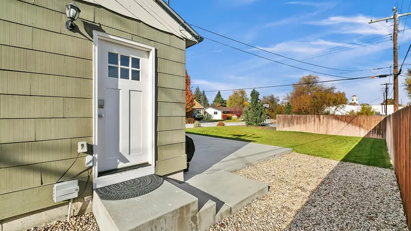 Back door with steps down to a concrete driveway and side yard.