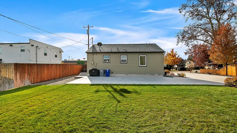 Back of the home with a concrete parking pad and lawn.